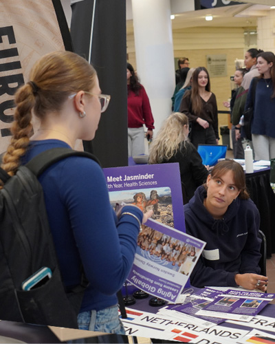 students in front of a desk talking about exchange opportunities