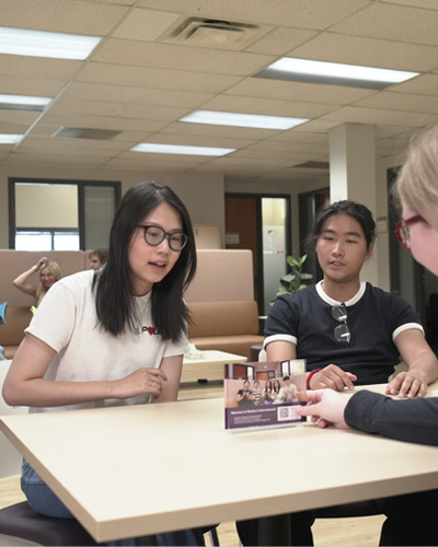 three students discussing something at a table
