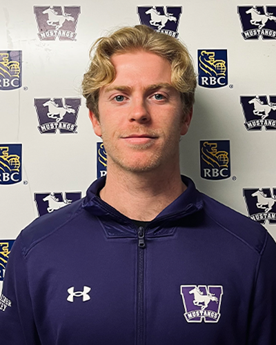 Riley Cousins wearing a purple varsity jacket standing in front of the western athletics backdrop