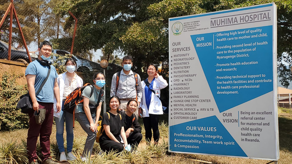 Students standing in front of a Muhima Hospital sign
