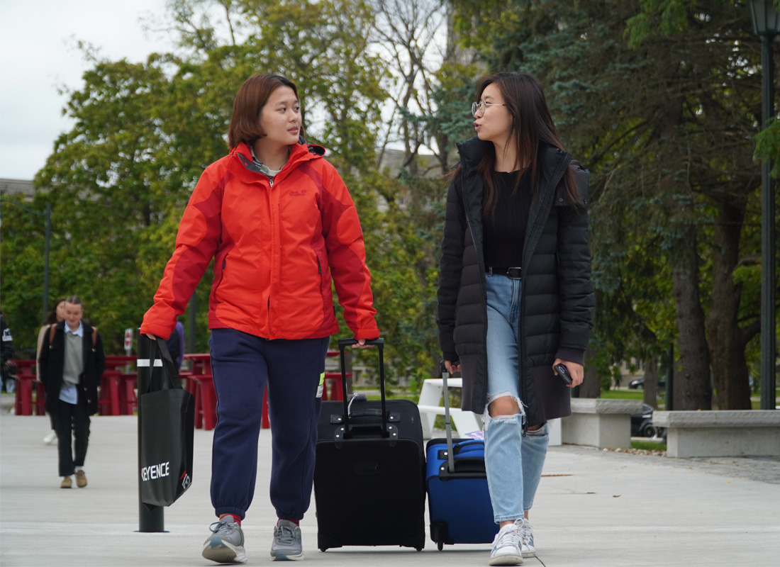 Students walking with a suitcase on campus