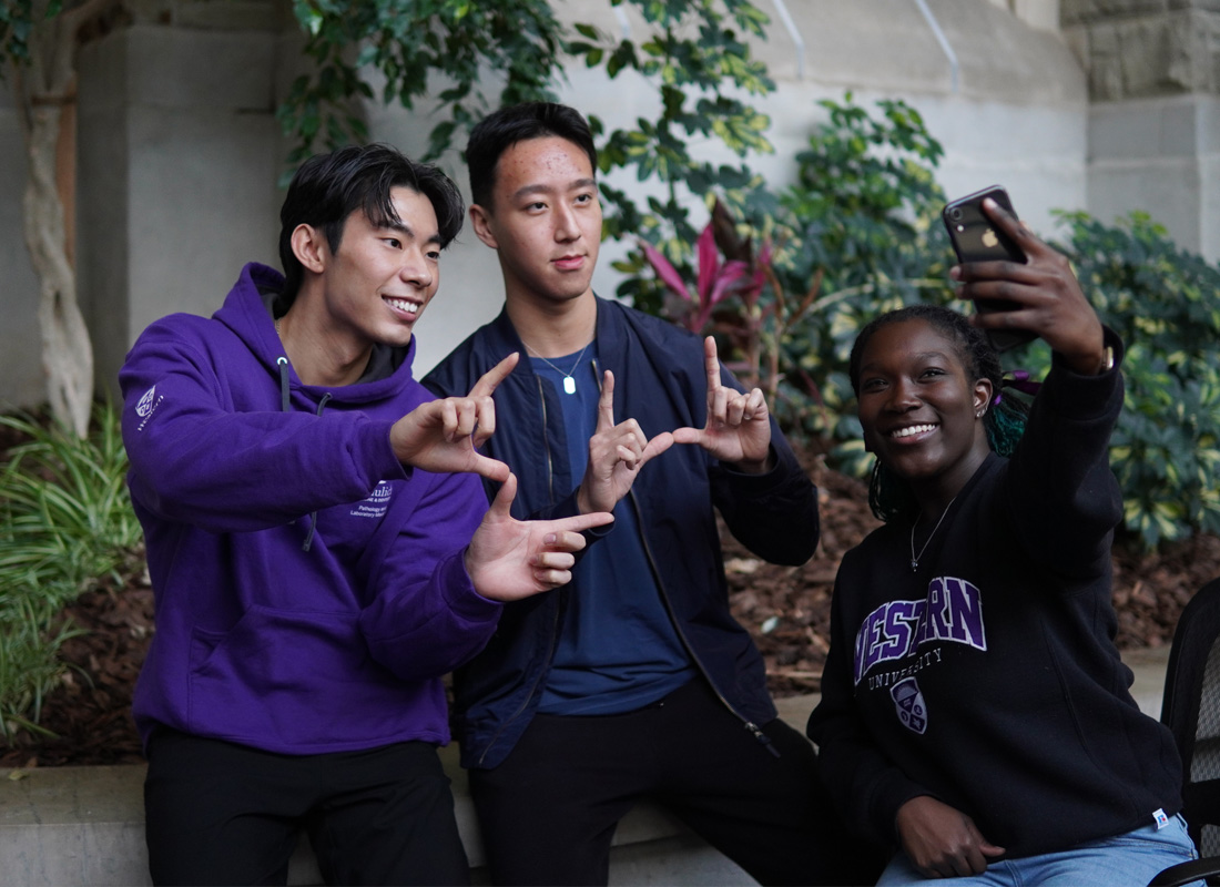 Students smiling, taking a selfie, and throwing up the Western W sign