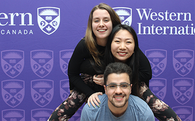 three students vertically stacked, smiling to camera