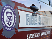 side of fire safety van with the fire safety logo bar around the Western crest. The red door also says "fire safety, emergency management"