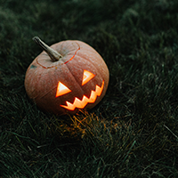 jack o'lantern lit up sitting on dark grass